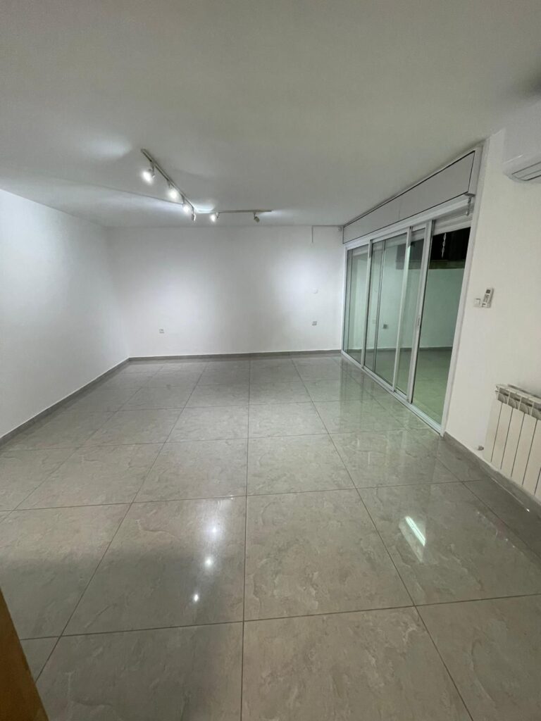 Bright empty living room with large sliding glass doors in French Hill, Jerusalem.