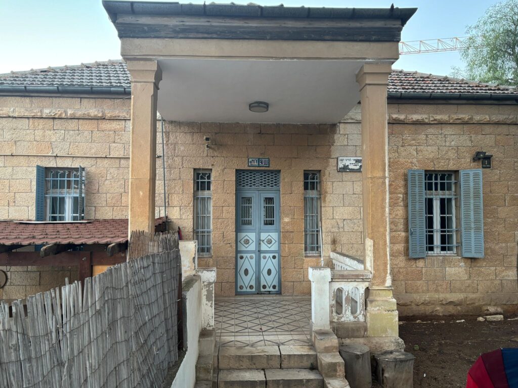 Stone house with a small front porch and blue shutters on the windows.