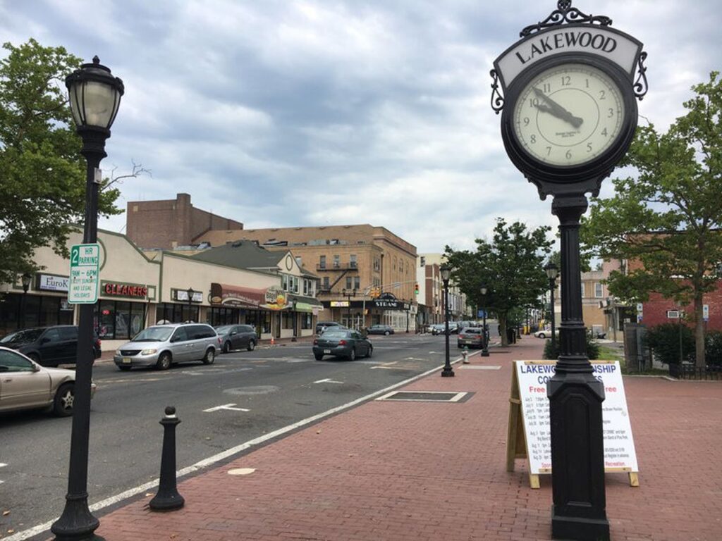Historic downtown Jackson, NJ with shops, cars, and a prominent Lakewood clock on a cloudy day.