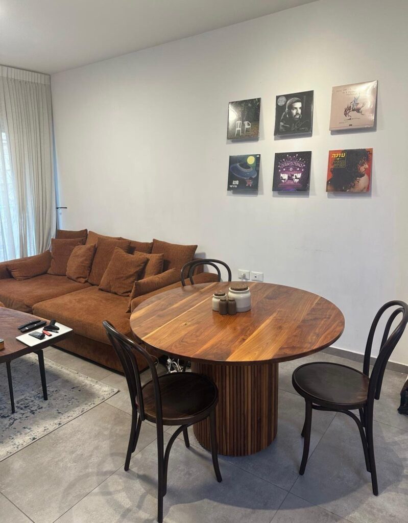 Vintage wooden dining table with black chairs and cozy brown sofa in modern living room.