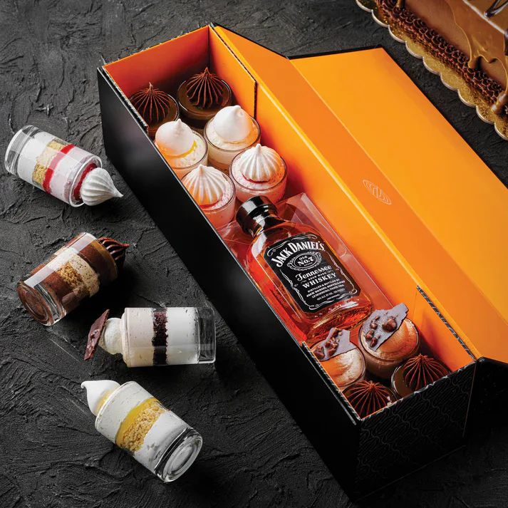 Miniature dessert jars with whipped cream and chocolate toppings, with Jack Daniel's whiskey bottle in a gift box.
