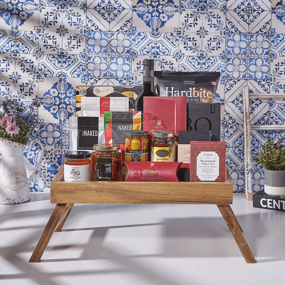 Assorted gourmet food and snack gifts on a wooden tray with blue and white patterned tiles in the background.