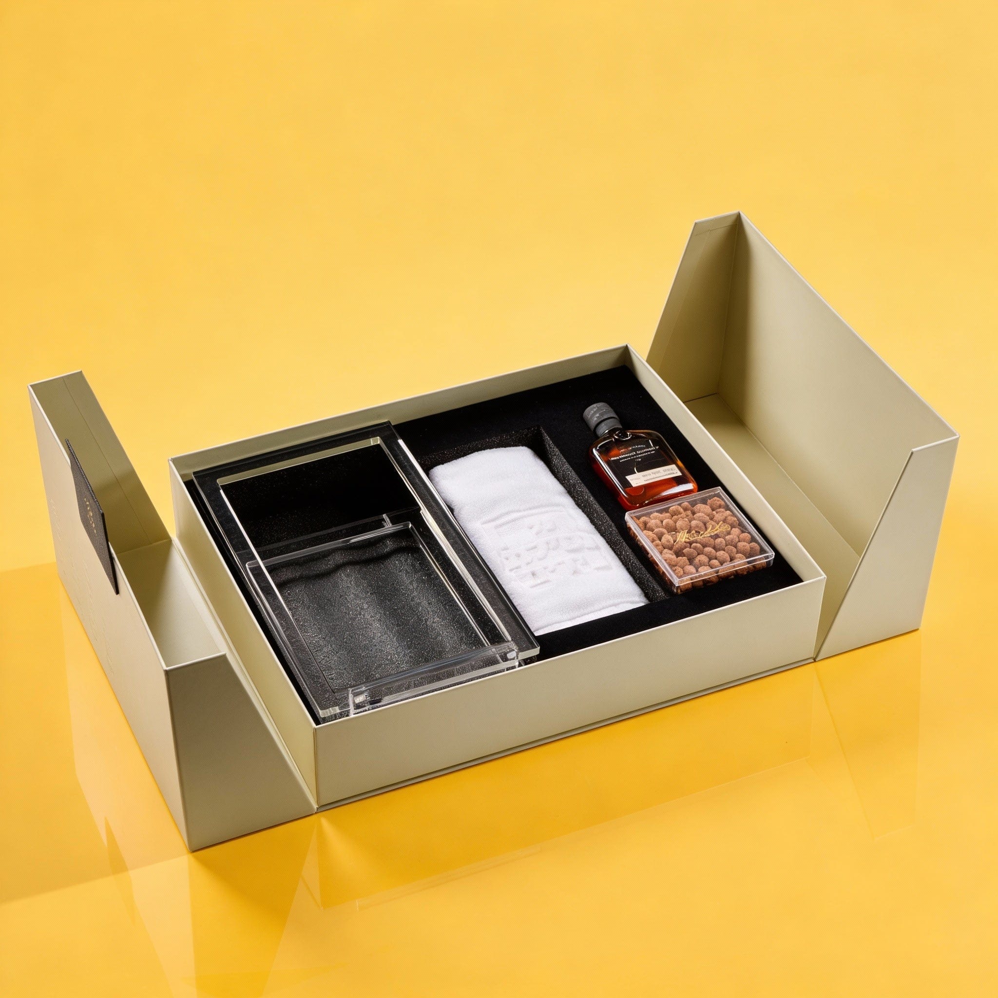 Luxurious gift set with glass tray, towel, liquor bottle, and chocolates in elegant box.