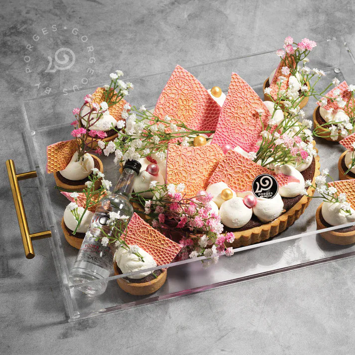 Elegant dessert tart with pink and white decorations, flowers, and a water bottle.