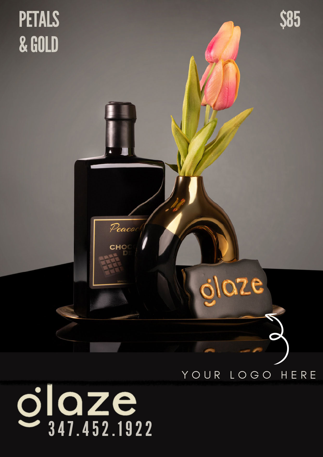 Beautiful floral and chocolate gift arrangement with a black bottle, pink tulip, and decorative blac.