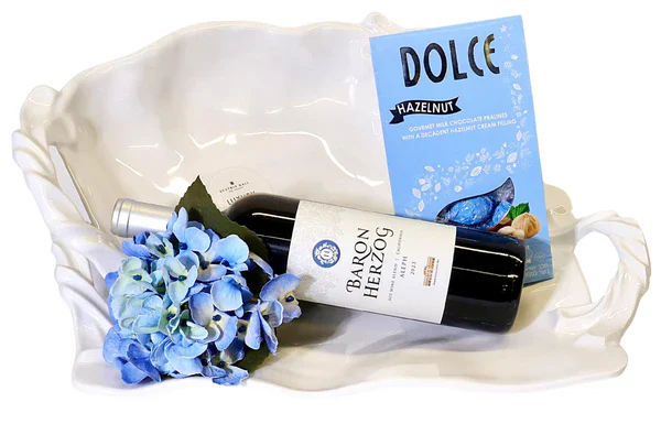 Luxurious gift basket featuring wine, chocolates, and blue hydrangea flowers for celebrations.
