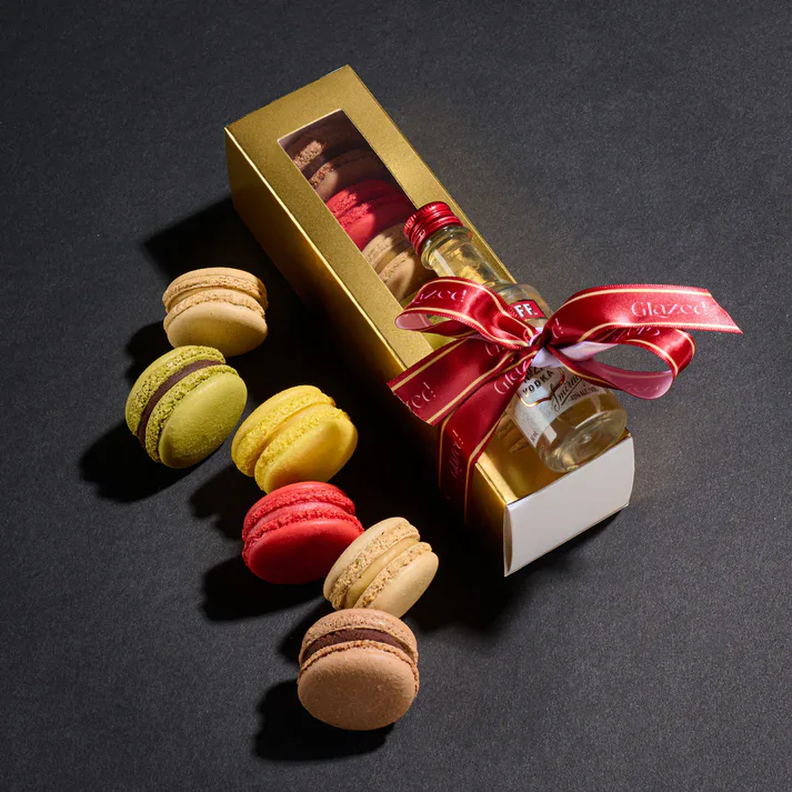Delicious macarons in various colors with a champagne bottle and gift box for celebrations.