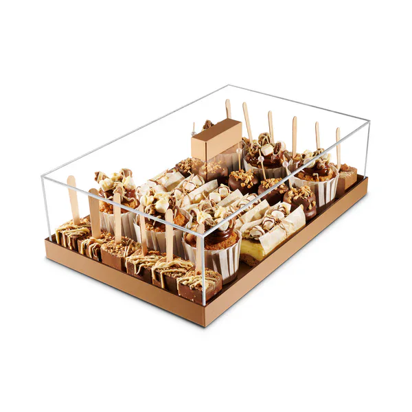 Assorted chocolate and vanilla desserts with toppings, presented in a clear display box for easy sel.