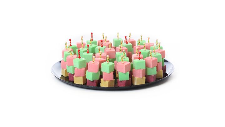 Colorful birthday cake with pink, green, and yellow frosting and lit candles on top.