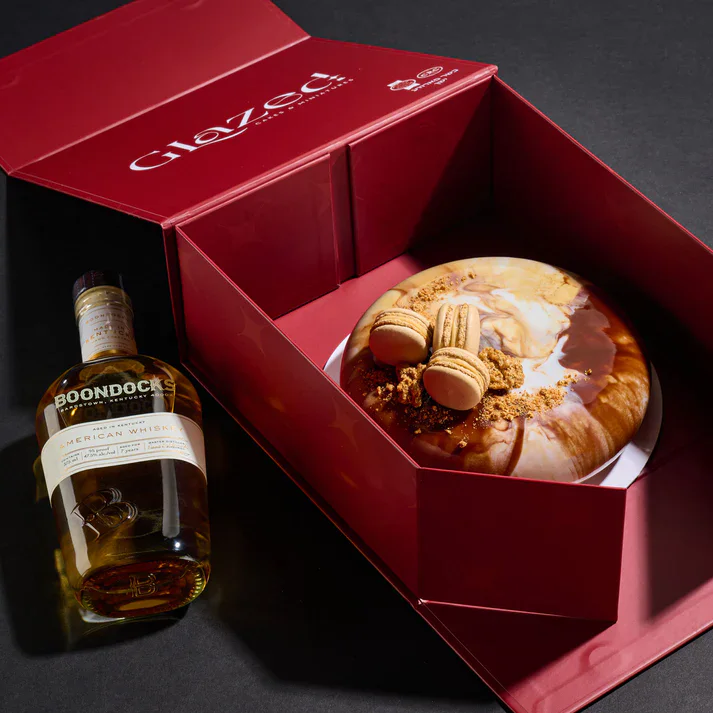 Delicious chocolate cake topped with macarons, presented in a stylish red gift box, perfect for cele.