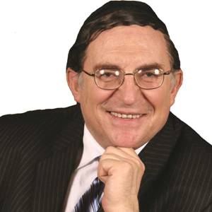 A person smiling confidently, wearing glasses and a suit, with a thoughtful pose.